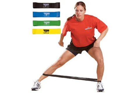 Woman wearing red t-shirt and black shorts demonstrating resistance loop bands in black, blue, green, and yellow on white bac