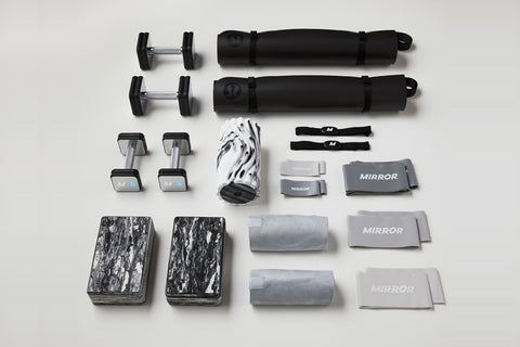Lululemon Studio Mirror with black carrying cases, yoga mats, water bottle, towels, and accessories displayed on white backgr
