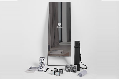 Lululemon Studio Mirror Pro with reflective surface, displayed with accessories including black carrying case, gray yoga mat,