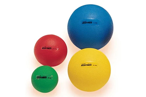Four Heavymed medicine balls in green, red, yellow, and blue rubber, arranged by size on white background