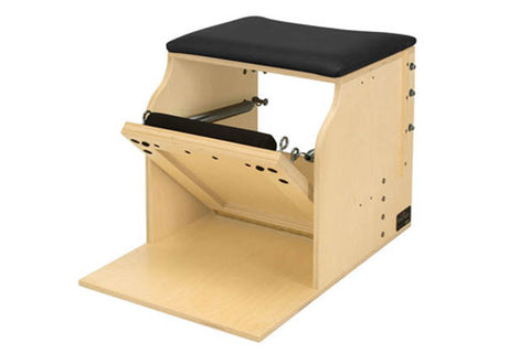 Natural wood Pilates low chair with black cushioned seat, single pedal mechanism, and open front platform on white background