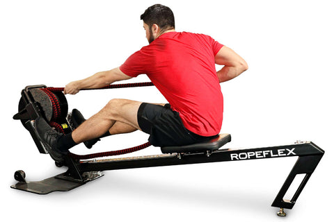 Man in red t-shirt and black shorts using black Ropeflex RX3200 rowing machine with rope handles on white background