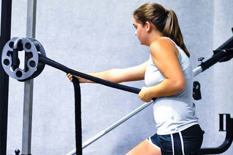 Woman using black rope trainer attachment with circular weight plate on exercise machine during workout