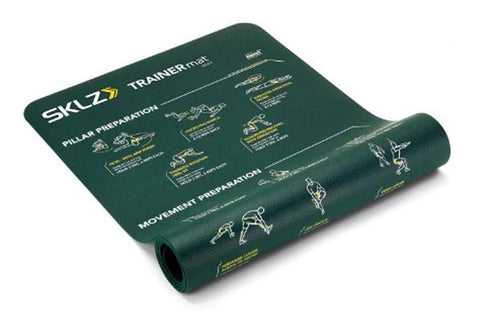 Dark green SKLZ Trainer Mat with white and gold instructional exercise diagrams printed across surface, partially rolled to s