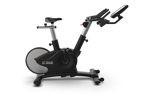 TRUE Surge indoor exercise bike with black and silver frame, white flywheel, adjustable seat and handlebars, digital display 