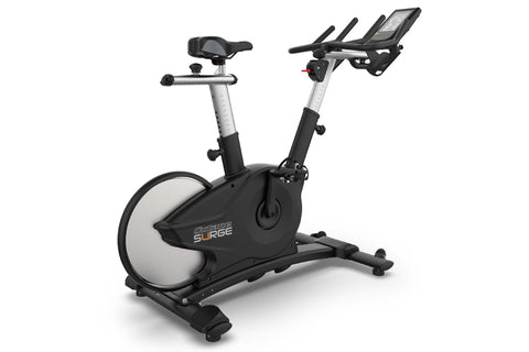 TRUE Surge indoor exercise bike with black and silver frame, white flywheel, adjustable seat and handlebars, digital display 