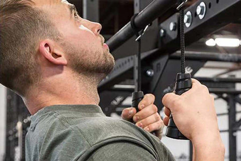 Man using black spiral strength grips on overhead bar, worn in gym setting