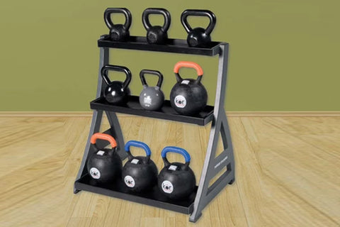 Three-tier kettlebell rack with gray steel frame and black shelves holding nine black kettlebells with colored handles, on wo