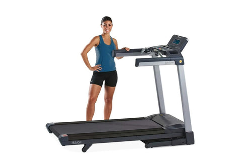 Woman in blue tank top and black shorts standing on black and silver LifeSpan TR3000i folding treadmill with digital console