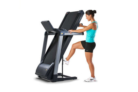 Woman in blue tank top and black shorts standing on black and silver LifeSpan TR3000i folding treadmill with digital console