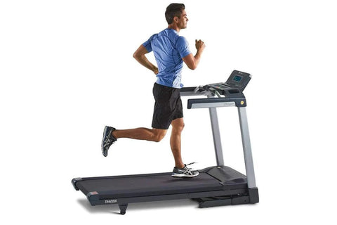 Man running on black and gray folding treadmill with digital console, wearing blue shirt and black shorts