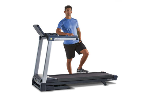 Man running on black and gray folding treadmill with digital console, wearing blue shirt and black shorts