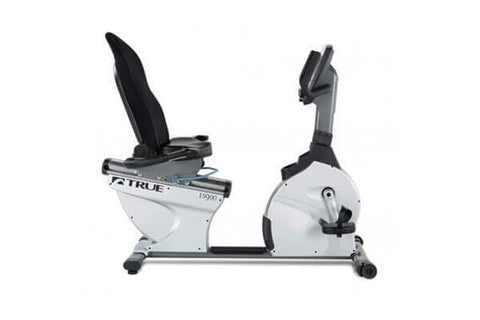 TRUE ES900 recumbent exercise bike with white frame, black seat and handlebars, digital display, and foot pedals on white bac