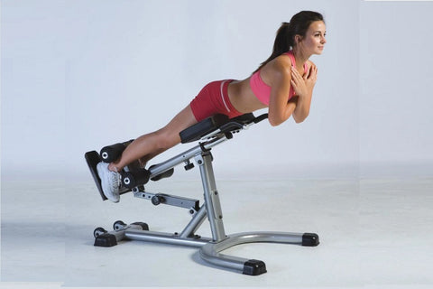 Gray adjustable hyper-extension bench with dual black leg extension pads, padded seat, and integrated dumbbell holders on whi