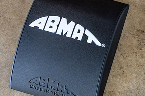 Black curved abdominal mat with red Warrior logo on top, on white background