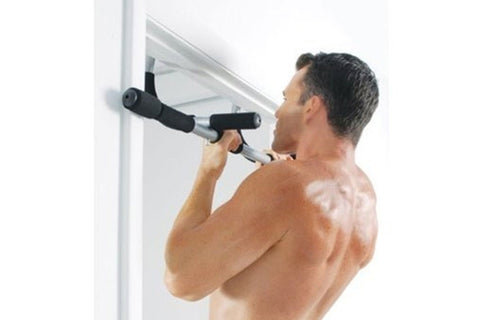 Shirtless man performing pull-up on black and silver door-mounted pull-up bar installed on white door frame