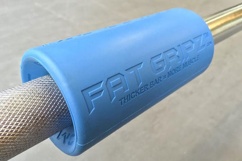 Blue foam barbell grip adapter with "Fat Gripz" branding on metal bar, designed to increase grip thickness for strength train