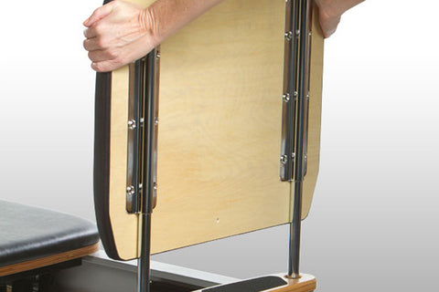 Peak Pilates Fit Reformer with black upholstered platform, white barrel, natural wood footbar and handles, metal spring mecha
