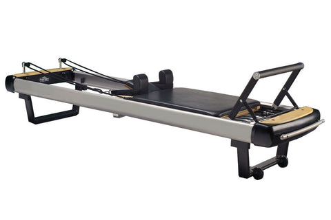 Pilates reformer with gray frame, black footplate, wooden accents, and adjustable carriage on white background