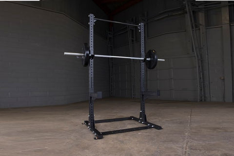 Purple and black steel half squat rack with barbell and weight plates in industrial gym setting