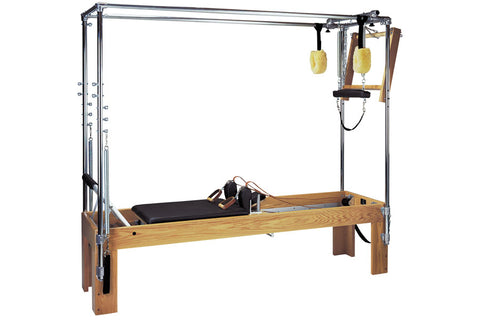 Pilates Cadillac Convertible with wood base, metal frame, black pad, and yellow spring handles on white background